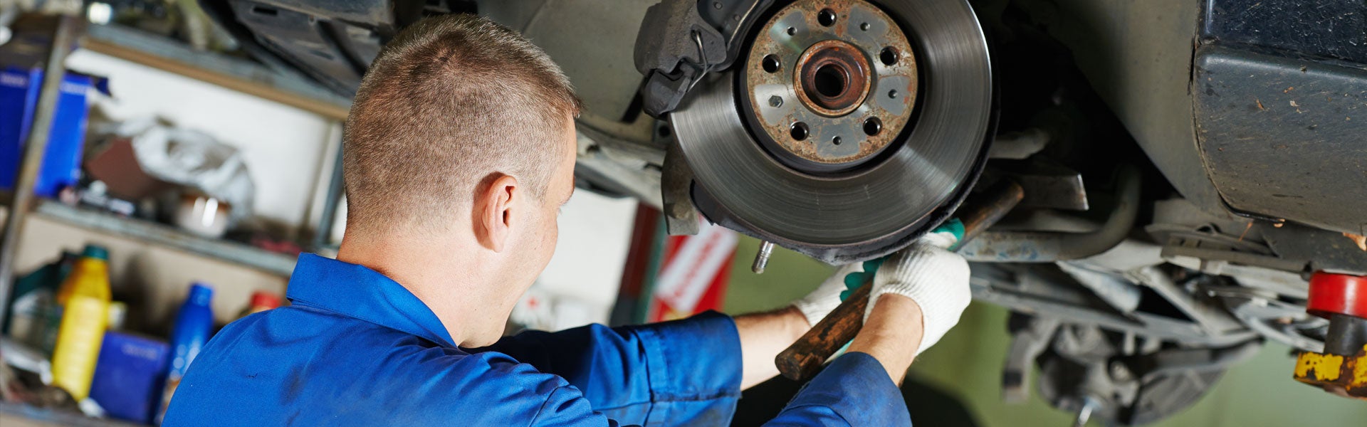 Technician servicing a brake rotor and caliper on a raised vehicle