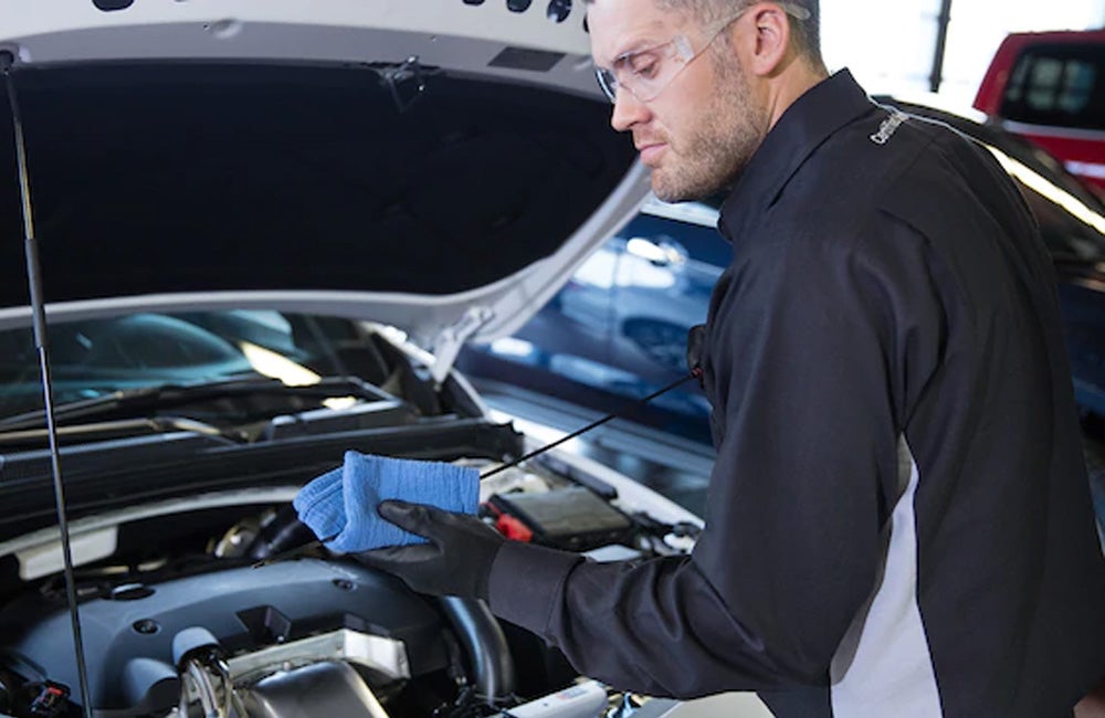 Service technician checking engine oil during Chevrolet maintenance