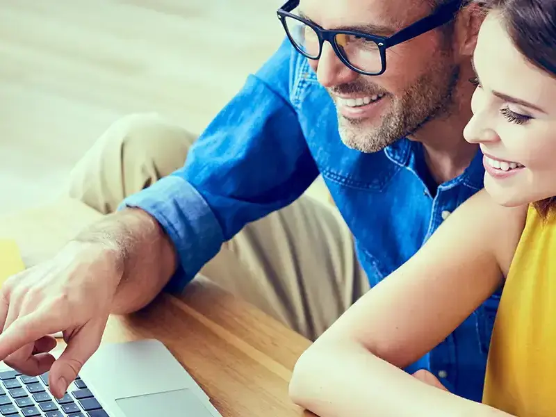 Man and woman smiling at laptop screen